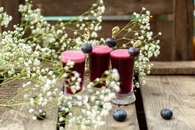 Eine Front Nahaufnahme sehen frische Cocktails um Blumen und auf der braunen Holzoberfläche