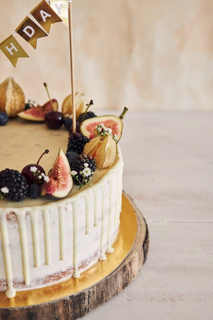 Kostenloses Foto eine fruchtige geburtstagstorte mit geburtstagstorte, früchten oben und weißem tropfen auf beige