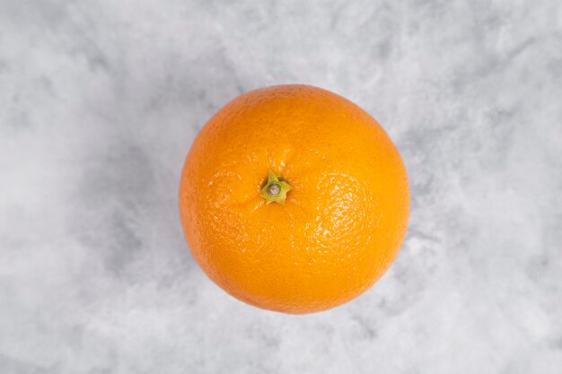 Eine ganze frische saftige Orangenfrucht auf Marmor gelegt