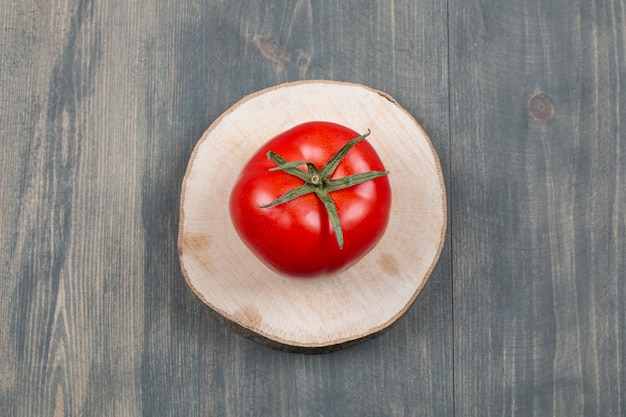 Kostenloses Foto eine ganze saftige tomate auf einem holztisch