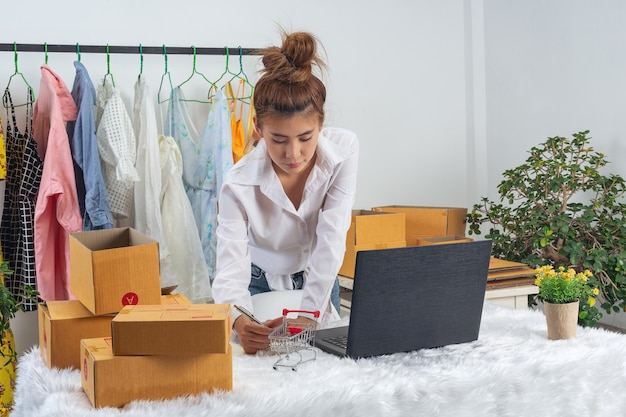 Kostenloses Foto eine geschäftsfrau arbeitet online und versucht, kunden zu hause büroverpackungen an der wand zu antworten.