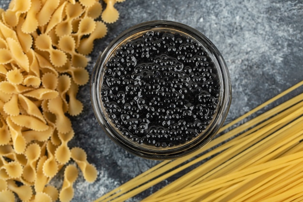 Kostenloses Foto eine glasplatte mit schwarzem störkaviar mit ungekochten nudeln.