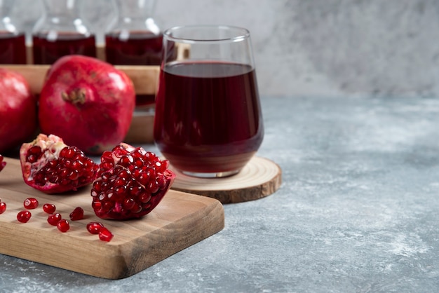 Eine Glasschale Granatapfelsaft auf einem Holzbrett.