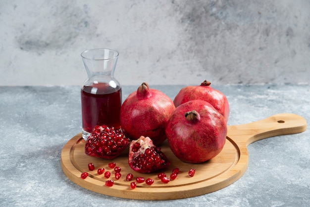 Eine Glasschale Granatapfelsaft auf einem Holzbrett.