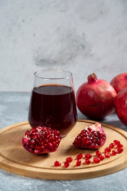 Kostenloses Foto eine glasschale granatapfelsaft auf einem holzbrett.