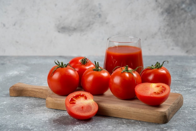 Eine Glasschale Tomatensaft auf einem Holzbrett.