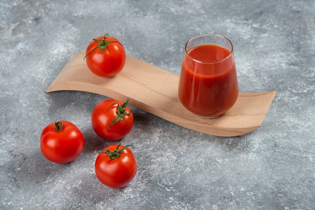 Eine Glasschale Tomatensaft auf einem Holzbrett.