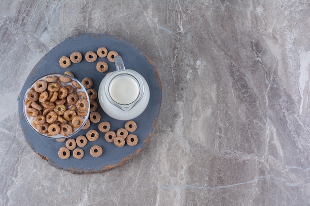 Eine Glasschüssel mit gesundem Joghurt mit knusprigen Cerealien und einem Glaskrug Milch.