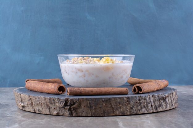 Eine Glasschüssel mit gesunden Cornflakes mit Milch und Zimtstangen