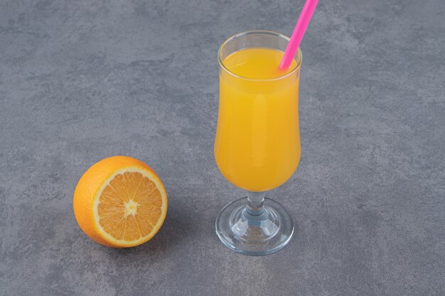 Eine Glastasse frischer Orangensaft mit einer Orangenscheibe und Strohhalm