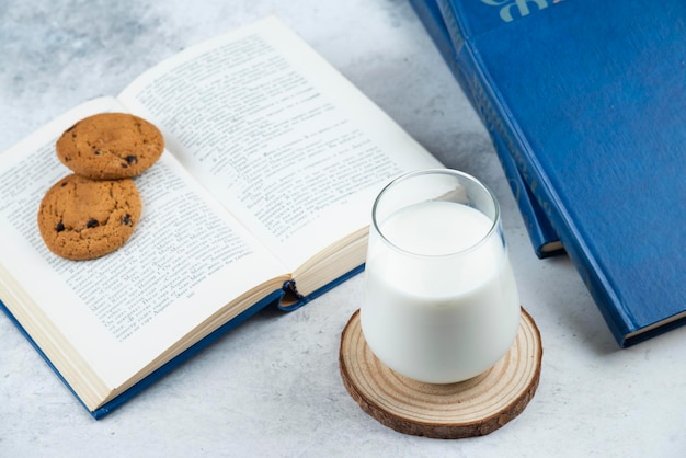 Eine Glastasse kalte Milch mit Schokoladenkeksen und Büchern.