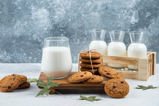 Eine Glastasse leckere Milch mit Keksen und Blättern.