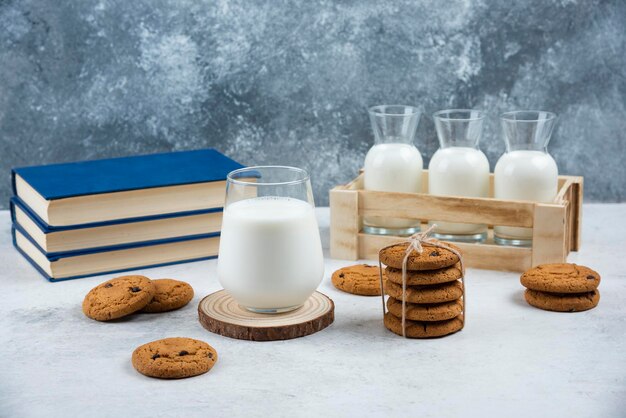 Eine Glastasse Milch mit Schokoladenkeksen auf einem Holzbrett.