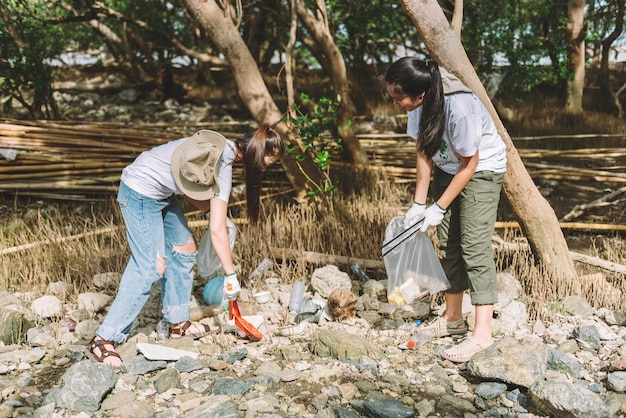 Eine Gruppe asiatischer, vielfältiger Menschen, die sich freiwillig für die Teamarbeit im Umweltschutz engagieren, helfen beim Sammeln von Plastik- und Schaummüll auf dem Parkgelände. Freiwilligenarbeit am Weltumwelttag