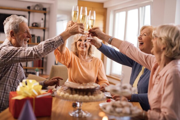 Eine Gruppe glücklicher reifer Menschen, die sich beim Toasten mit Champagner auf der Geburtstagsfeier amüsieren