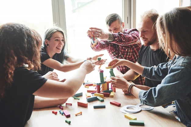 Eine Gruppe kreativer Freunde, die auf einem Holztisch sitzen. Die Leute hatten Spaß beim Brettspiel.