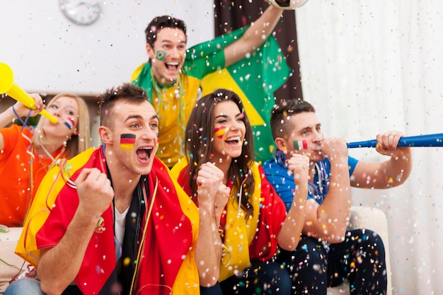 Eine Gruppe multiethnischer Menschen feiert den Sieg der Lieblingsfußballmannschaft