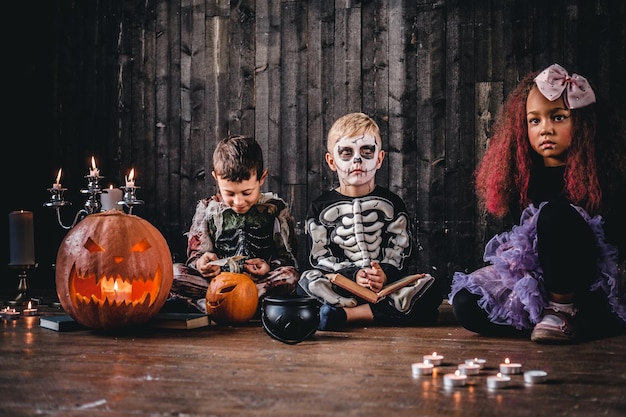 Eine Gruppe süßer gemischtrassiger Kinder in gruseligen Kostümen während der Halloween-Party in einem alten Haus. Halloween-Konzept.