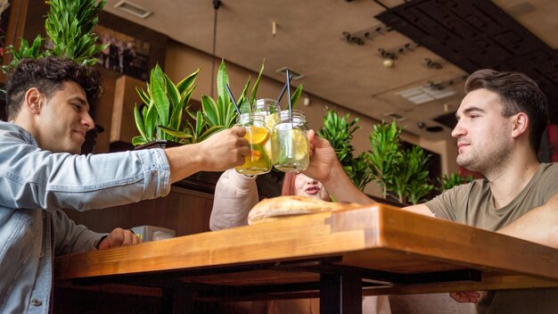 Eine Gruppe von Freunden, die sich in einer Kneipe ausruhen. Essen, Trinken, Essen auf dem Tisch. Freundschaft