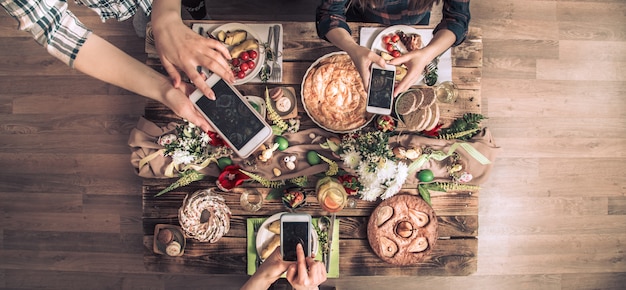 Eine Gruppe von Freunden macht ein Foto mit dem Handy, bevor sie zu Mittag essen. Draufsicht.