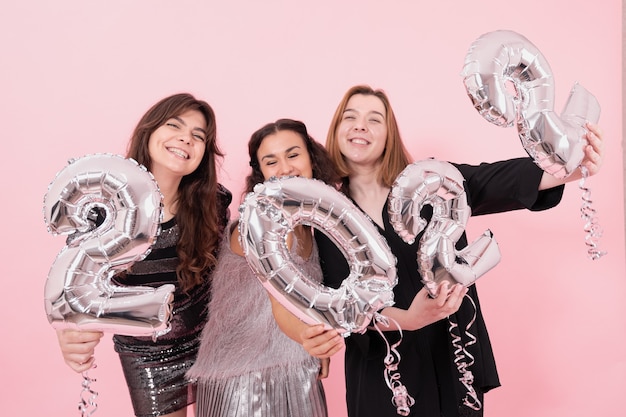 Eine Gruppe von Freundinnen mit silbernen Luftballons in Form der Zahlen