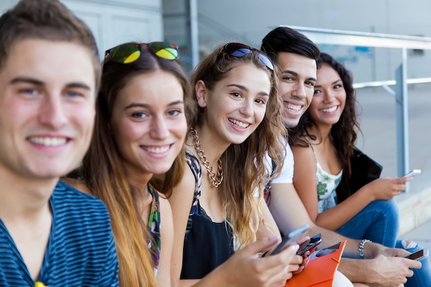 Eine Gruppe von Studenten, die Spaß mit Smartphones nach dem Unterricht haben.