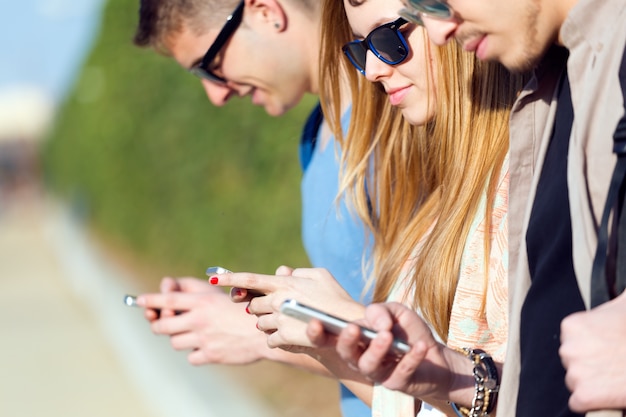 Eine Gruppe von Studenten, die Spaß mit Smartphones nach dem Unterricht haben.