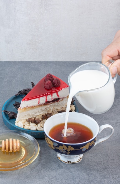 Kostenloses Foto eine hand, die milch in tasse kaffee auf grauem tisch gießt.