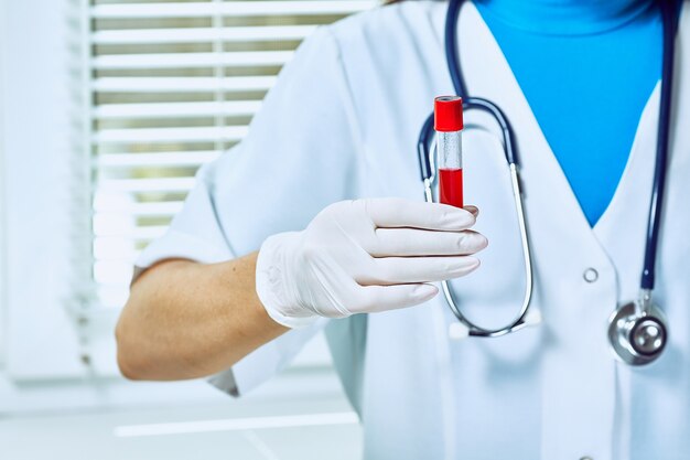 Eine hand in einem medizinischen handschuh hält ein reagenzglas mit dna.