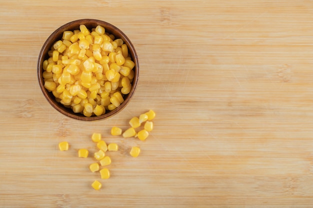 Eine hölzerne Schüssel Popcorn-Samen auf Holztisch.