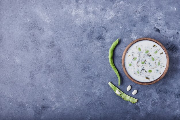 Eine hölzerne Tasse Joghurtsuppe mit Bohnen.