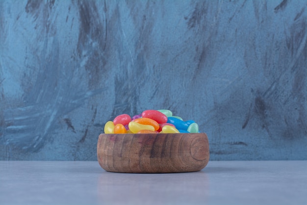 Eine holzschale mit bunten süßen jelly bean bonbons.