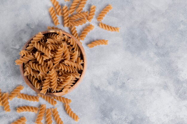 Eine Holzschale mit italienischen ungekochten trockenen Nudeln Fusilli. Hochwertiges Foto