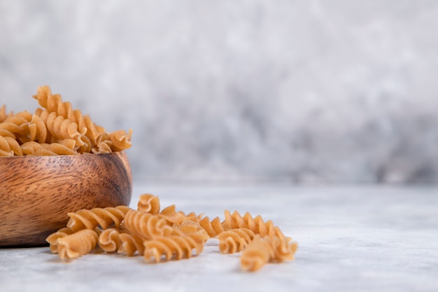 Eine Holzschale mit italienischen ungekochten trockenen Nudeln Fusilli. Hochwertiges Foto