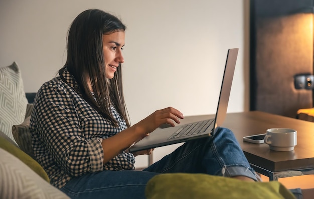 Kostenloses Foto eine junge frau arbeitet zu hause an einem laptop