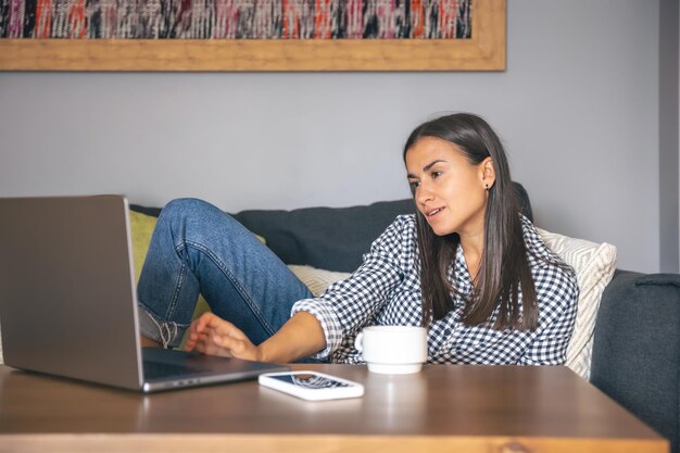 Eine junge Frau arbeitet zu Hause an einem Laptop