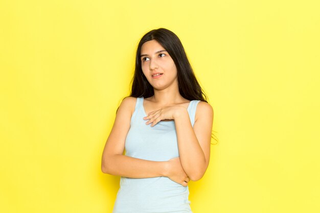 Eine junge Frau der Vorderansicht im blauen Hemd, das auf dem gelben Hintergrundmädchen-Posenmodell aufwirft