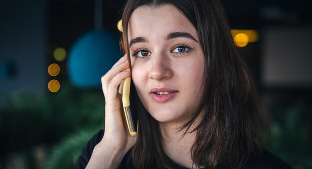 Eine junge Frau, die am Telefon spricht, Nahaufnahme, unscharfer Hintergrund