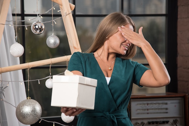 Eine junge Frau, die in der Nähe von Weihnachtskugeln steht und ein Weihnachtsgeschenk macht