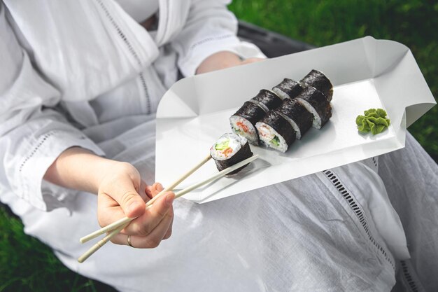 Eine junge Frau, die Sushi in der Natur isst, Maki-Rolle, Nahaufnahme