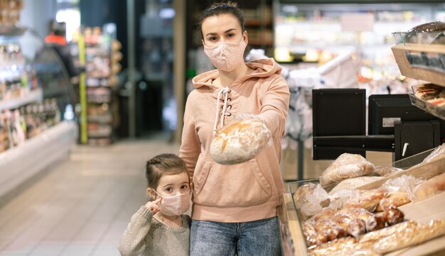 Eine junge Frau, die während einer Virusepidemie in einem Supermarkt einkauft. Trägt eine Maske im Gesicht.