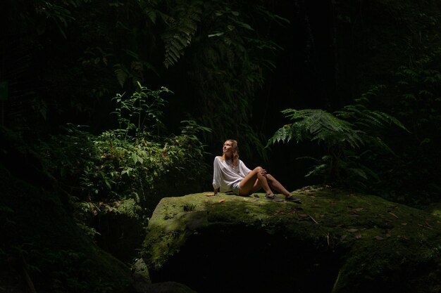Eine junge Frau im Dschungel lässt Rauchschwaden aus Vape