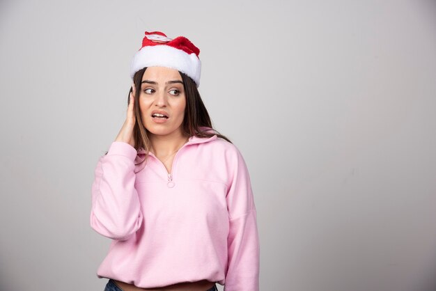 Eine junge Frau im roten Hut des Weihnachtsmannes, die weg schaut.