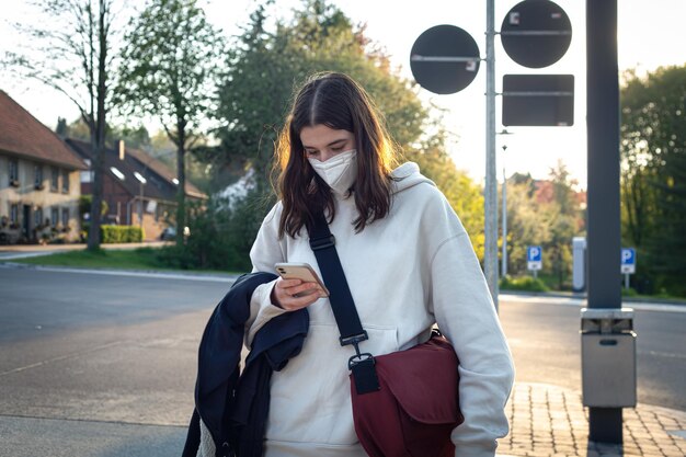 Eine junge Frau im Teenageralter wartet frühmorgens an einer Bushaltestelle auf einen Bus