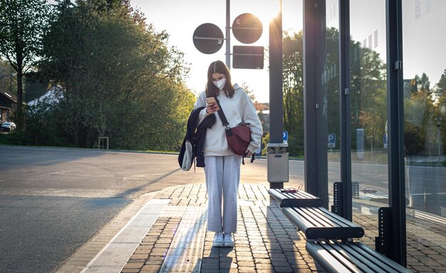 Eine junge Frau im Teenageralter wartet frühmorgens an einer Bushaltestelle auf einen Bus