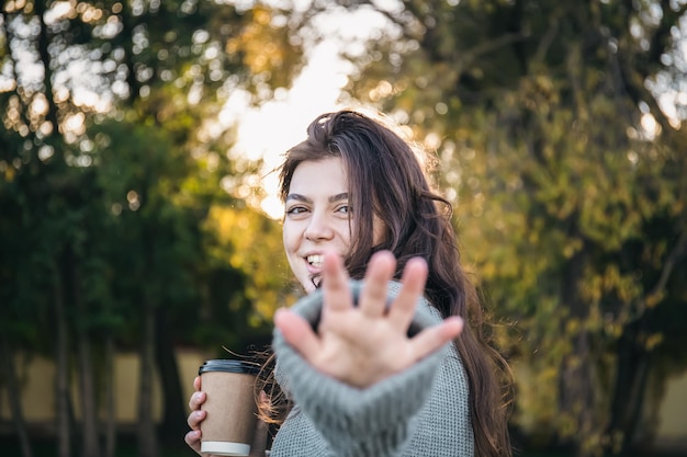 Eine junge Frau in einem Pullover mit einer Tasse Kaffee in der Natur