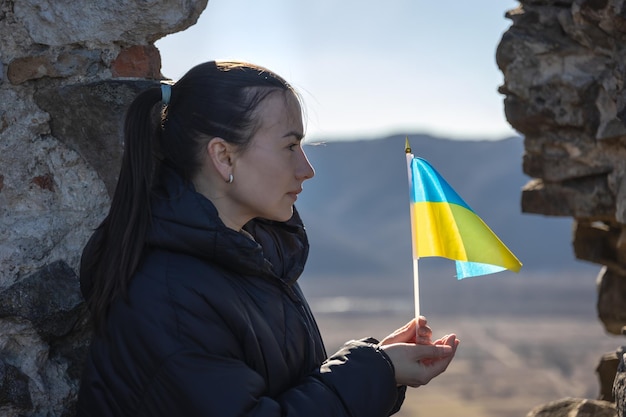 Eine junge frau mit der flagge der ukraine in ihren händen