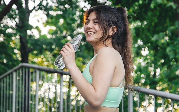 Eine junge Frau mit einer Flasche Wasser im Training im Stadion