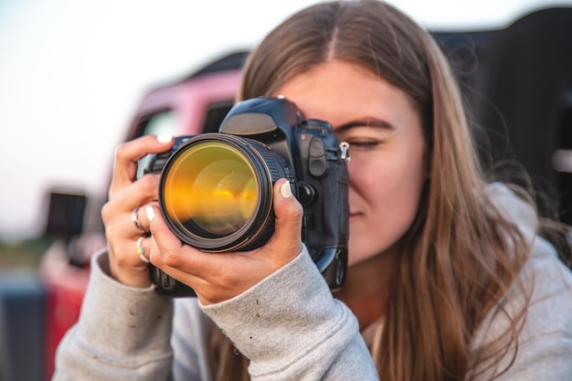 Eine junge Frau mit einer professionellen Kamera macht ein Foto in der Natur