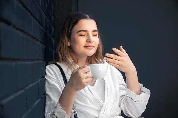 Eine junge Frau mit Kaffeetasse im schwarzen Café-Interieur